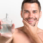 young-shirtless-smiling-man-showing-aftershave-lotion-spray-bottle